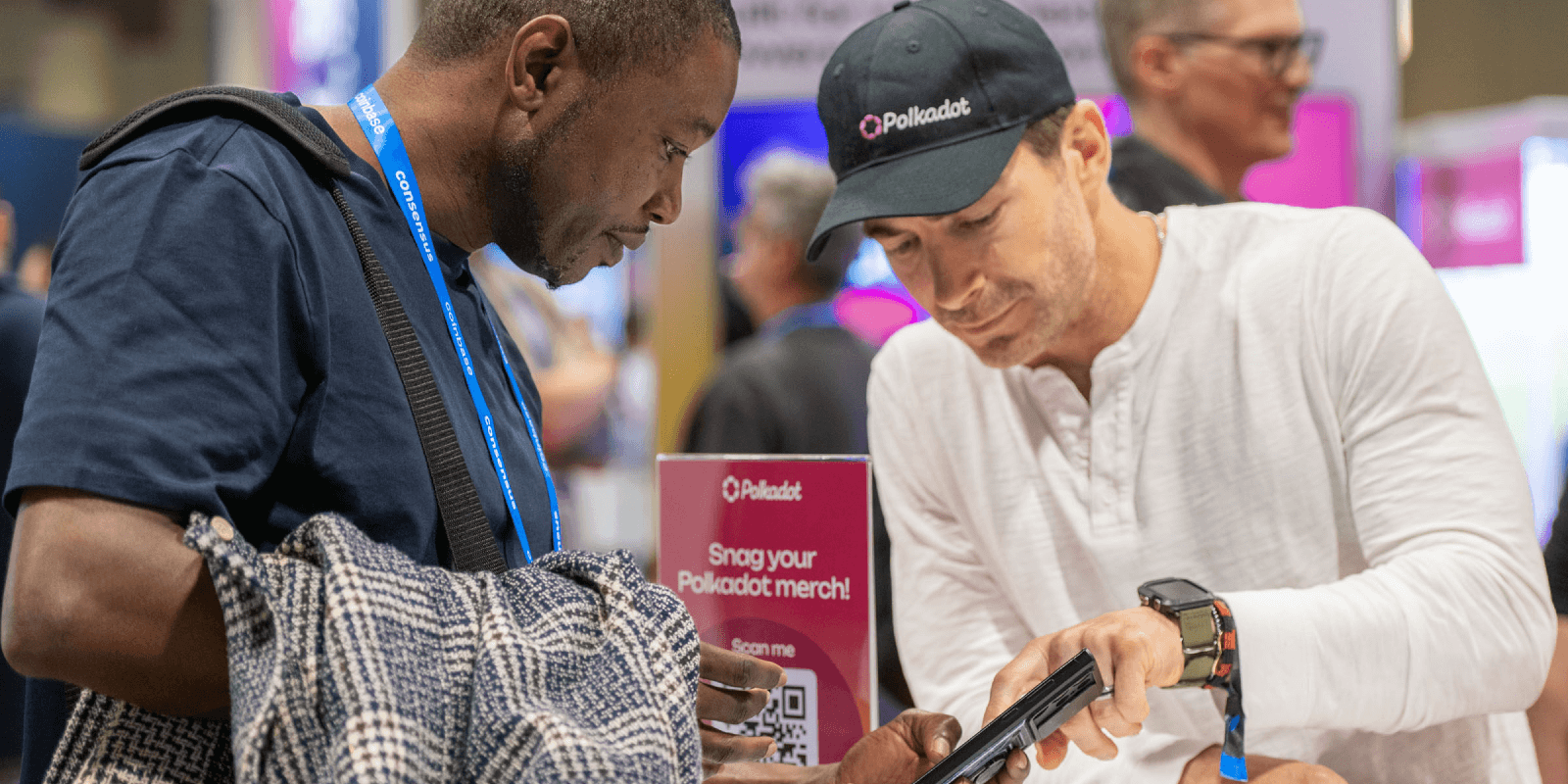 Polkadot team member assists an attendee with the onboarding flow at Consensus 2025, showing how to claim DOT tokens through a mobile experience.