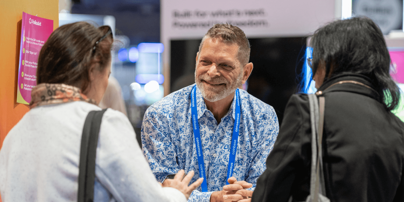 Attendees gather at the Polkadot booth during Consensus 2025, engaging in friendly conversation beside signage outlining the onboarding flow.