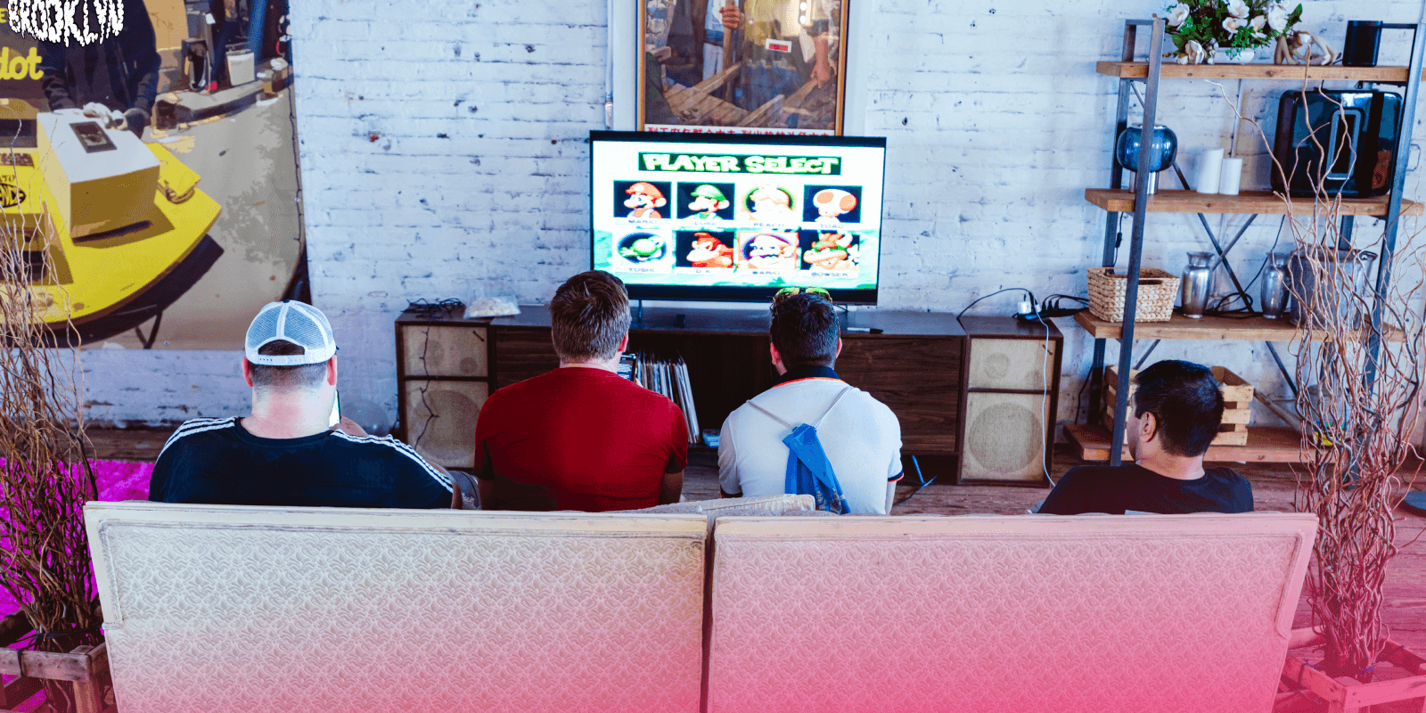Attendees sitting on a couch playing mario cart on a nintendo 64